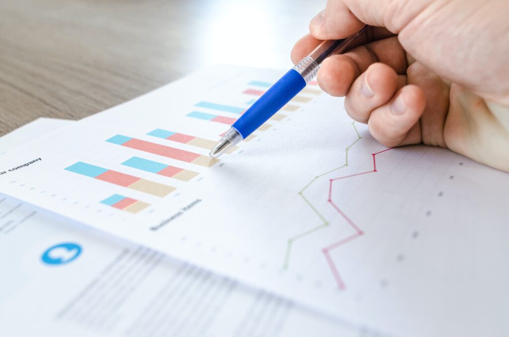 Close up of a person's hand holding blue pen, reading marketing reports.