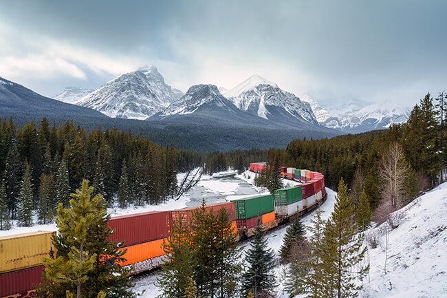 A freight train carrying container passing through the Bow Valley on winter at Morants Curve in Alberta