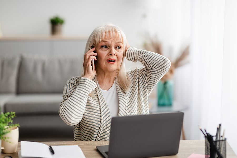 image of woman in distress on the phone with her laptop in front of her